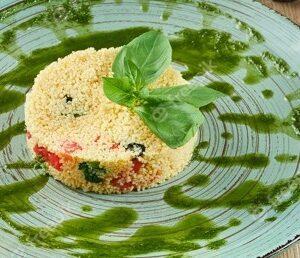 couscous with tomatoes pesto and basil on a blue plate on a wooden table healthy vegetarian food fitness nutrition close up view 207126 1979